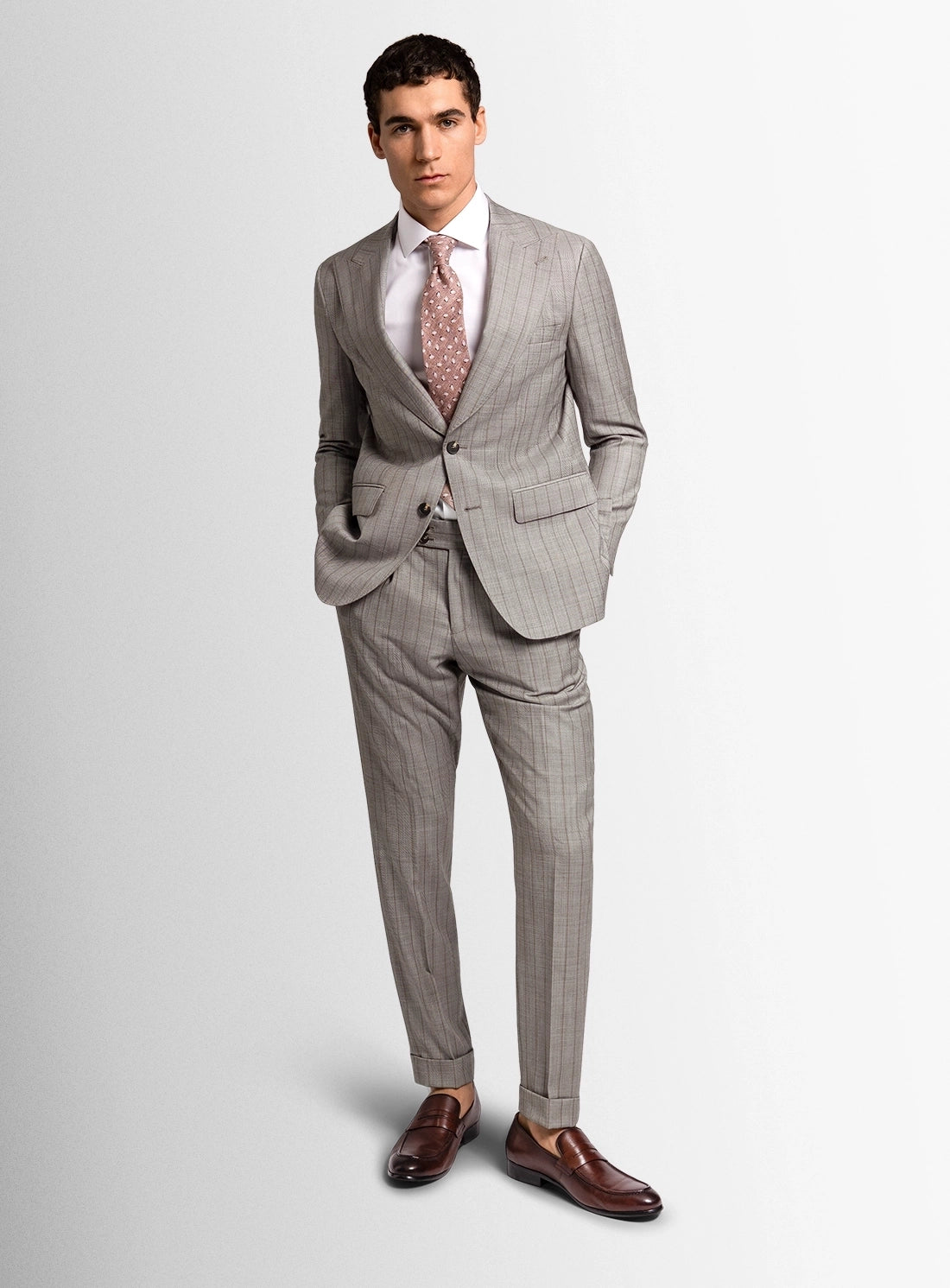 Man wearing a gray checkered suit with a white shirt and patterned tie on a light gray background