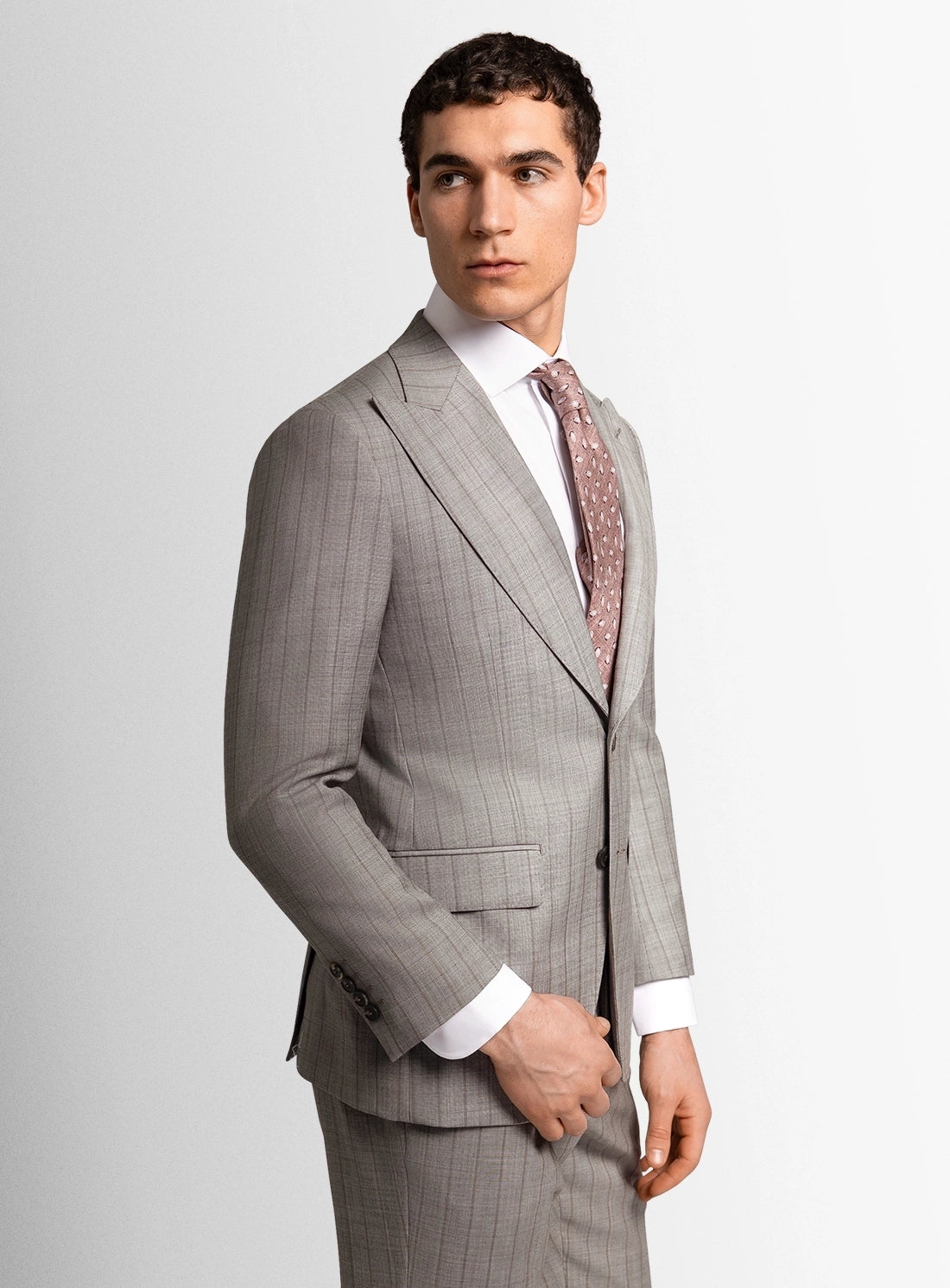 Man wearing a gray suit with a white shirt and patterned tie on a light gray background