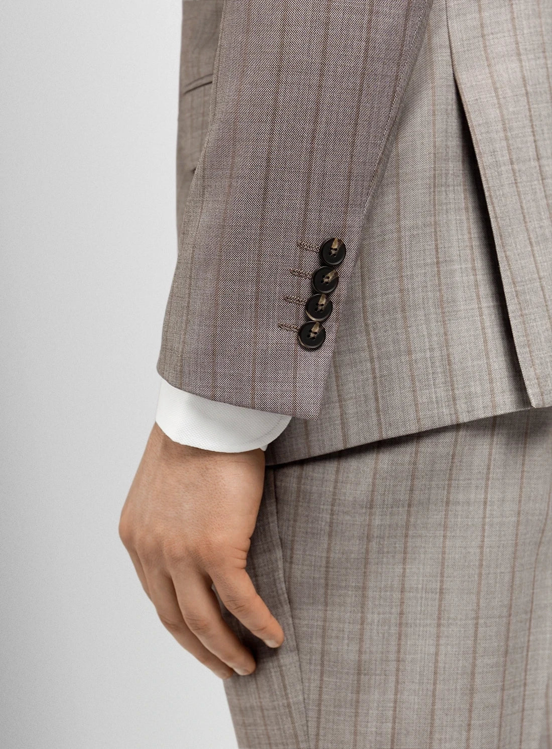 Close-up of a gray checkered suit with a hand wearing a white shirt cuff.