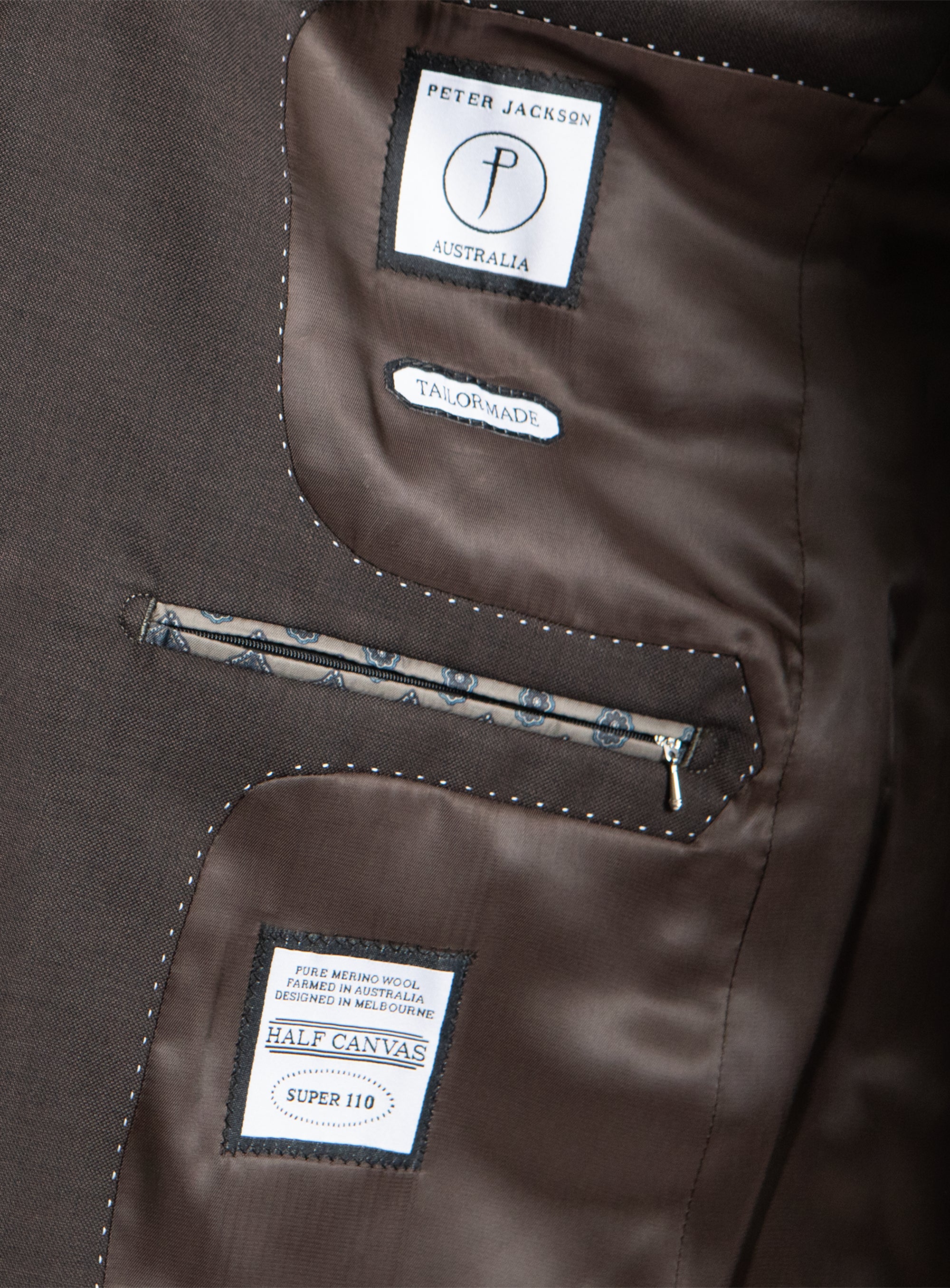 Close-up of a brown jacket with brand labels on the back pocket