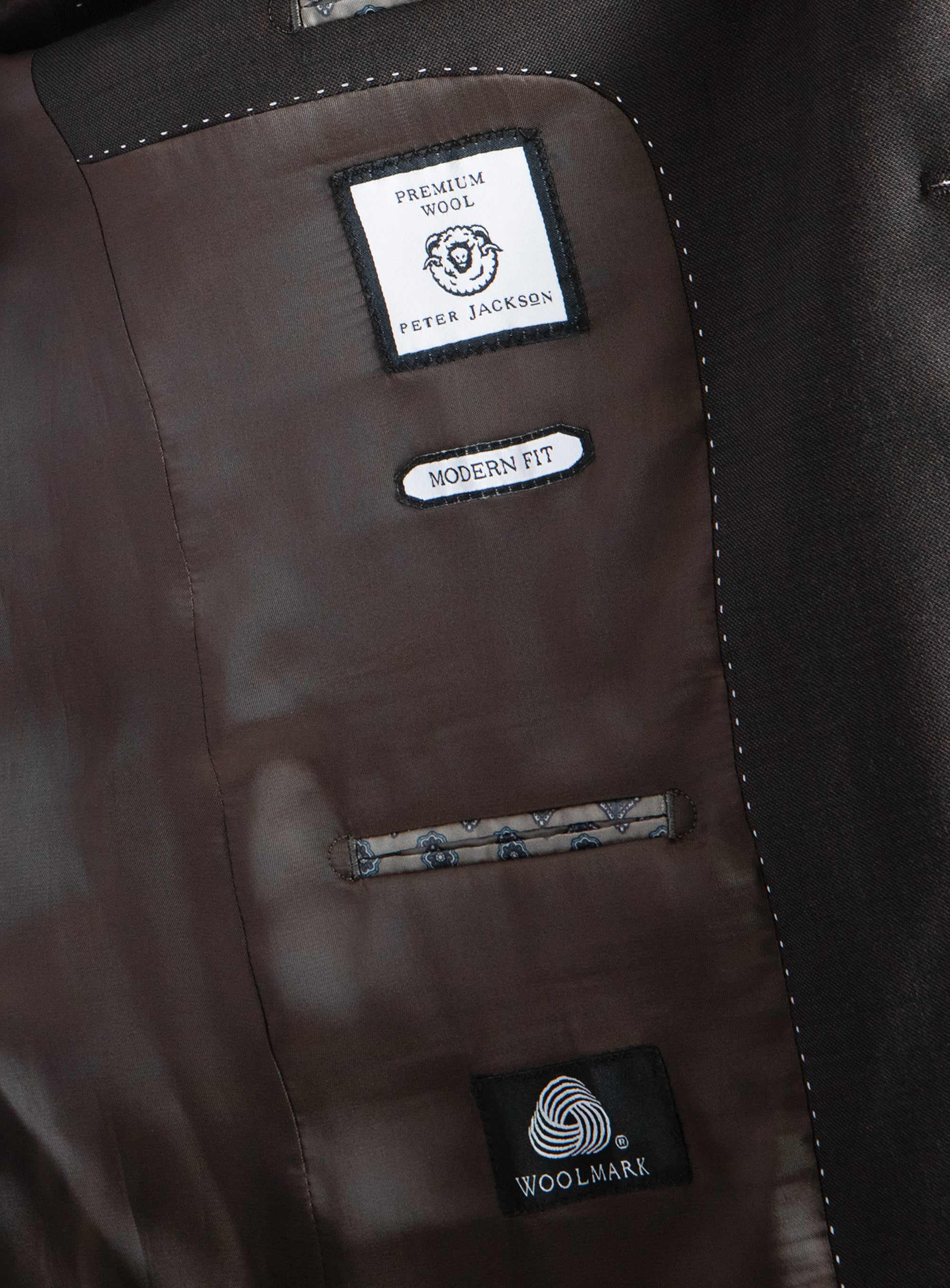 Close-up of a brown jacket with brand labels on a dark background