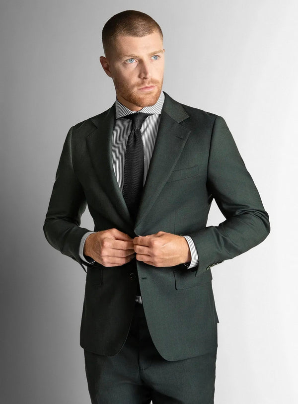 Man wearing a dark green suit with a striped shirt