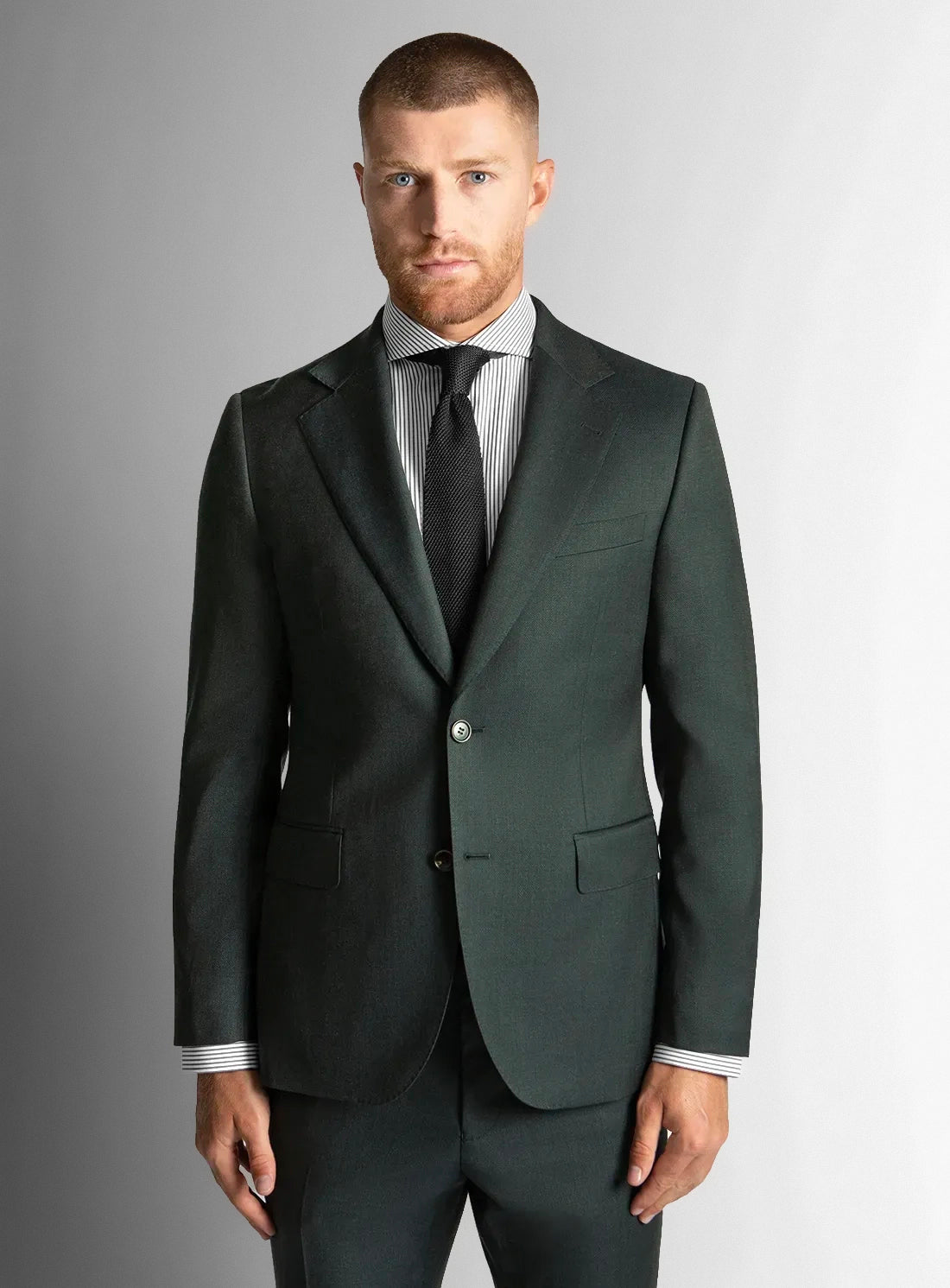 Man wearing a dark green suit with a striped shirt