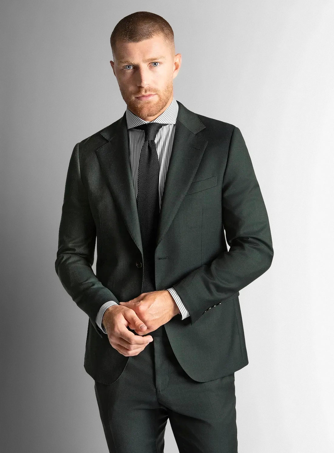 Man wearing a dark green suit against a white background