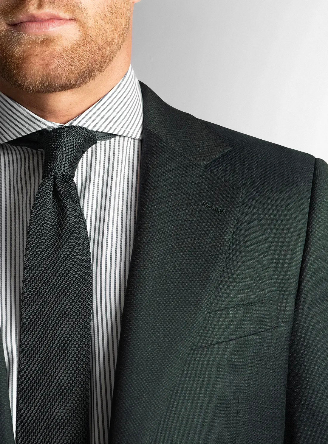 Close up of a man wearing a green suit and tie with striped shirt