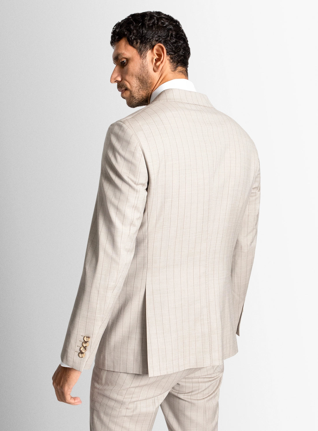 Man wearing a beige pinstripe suit on a light gray background