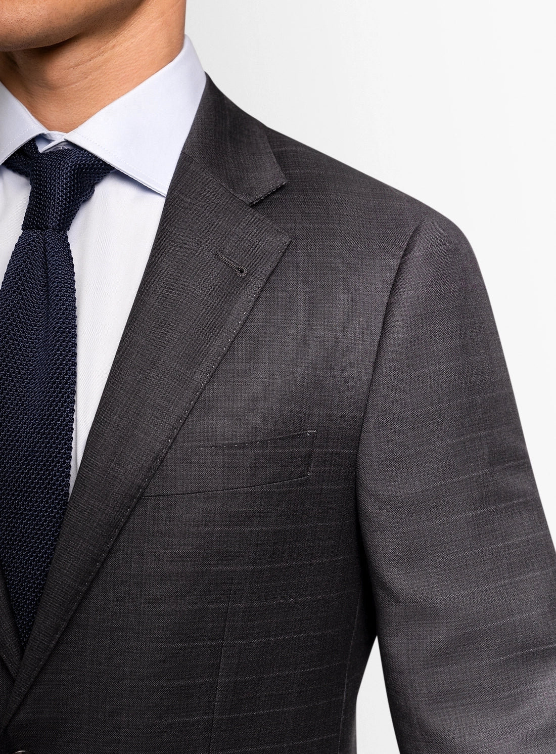 Gray suit jacket with a white shirt and dark tie on a light gray background