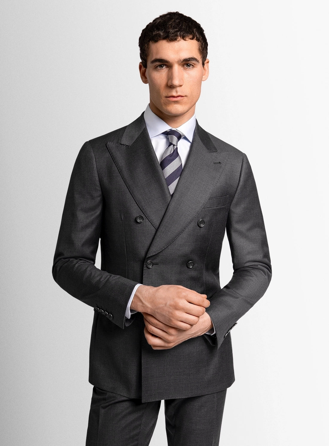 Man wearing a gray suit with a white shirt and striped tie on a light gray background