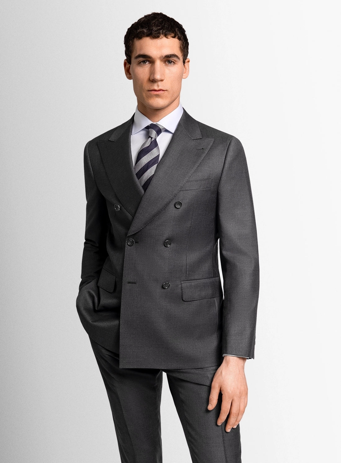 Man wearing a gray suit with a white shirt and striped tie on a light gray background