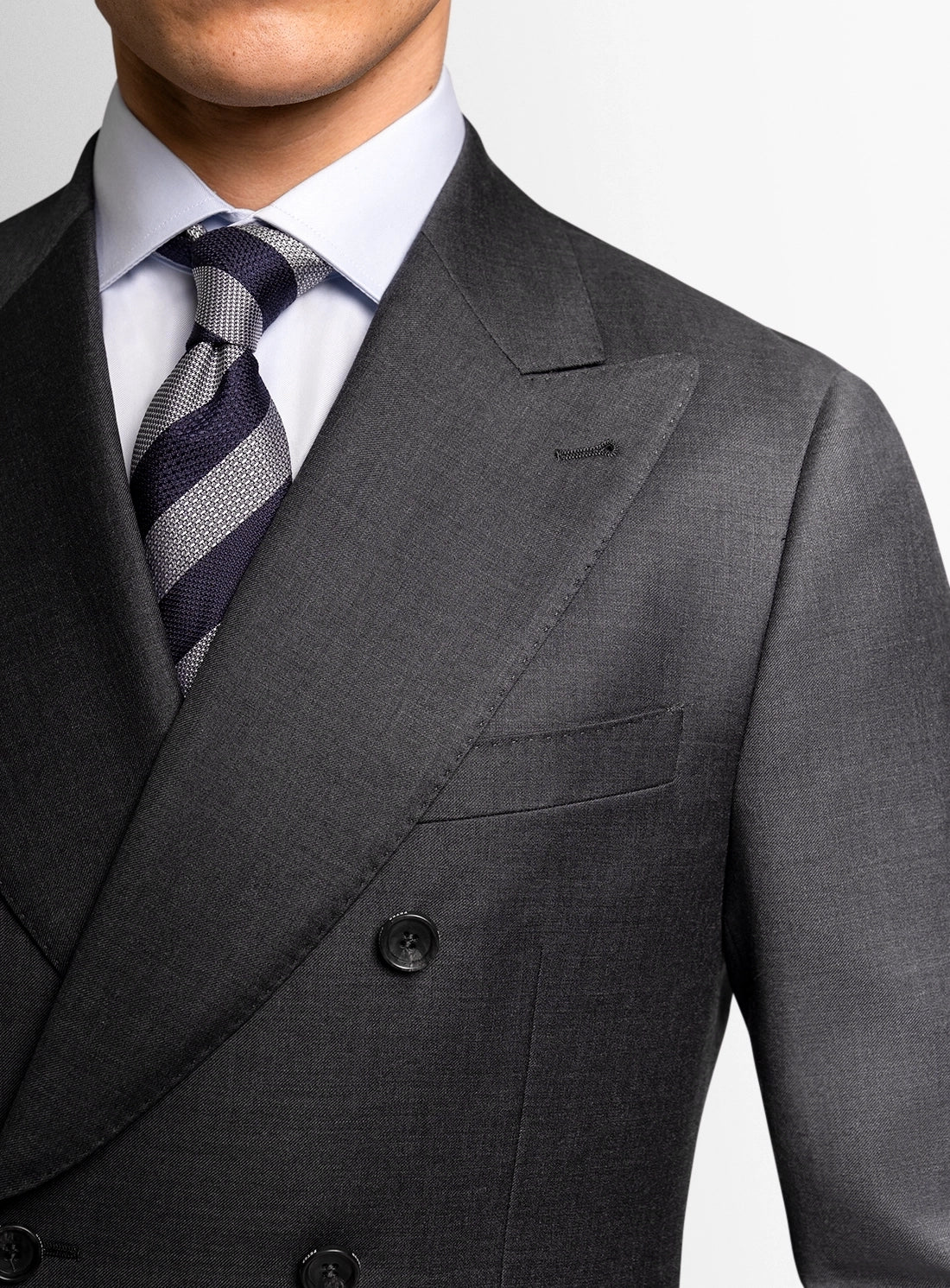 Gray suit jacket with a white shirt and striped tie on a plain background