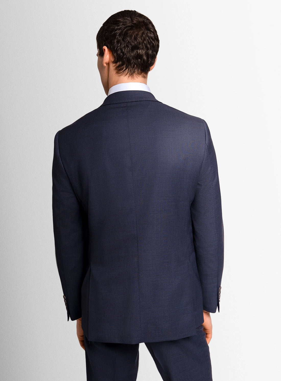 Man wearing a navy suit jacket on a light gray background