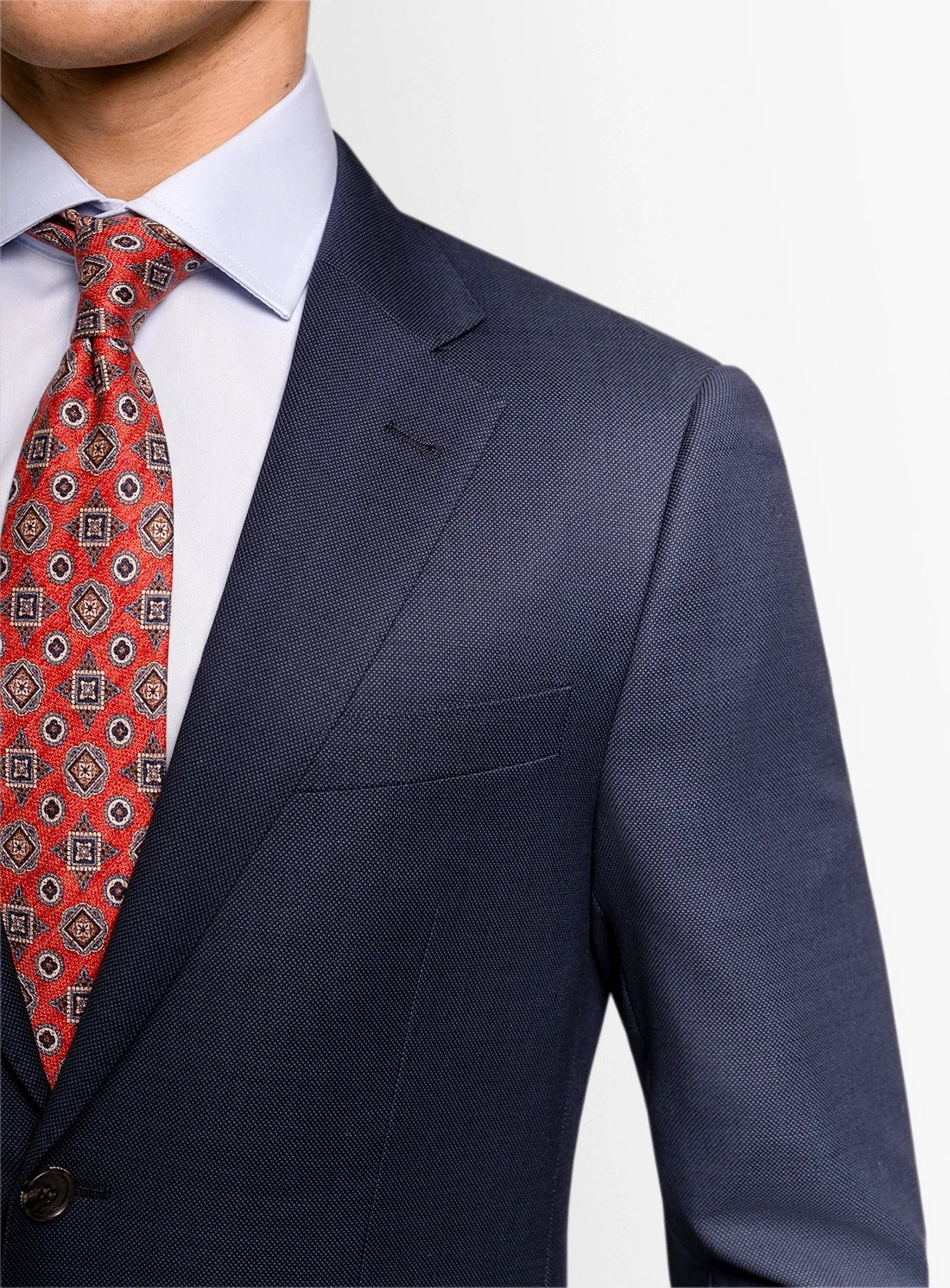 Navy suit jacket with a red patterned tie on a white background