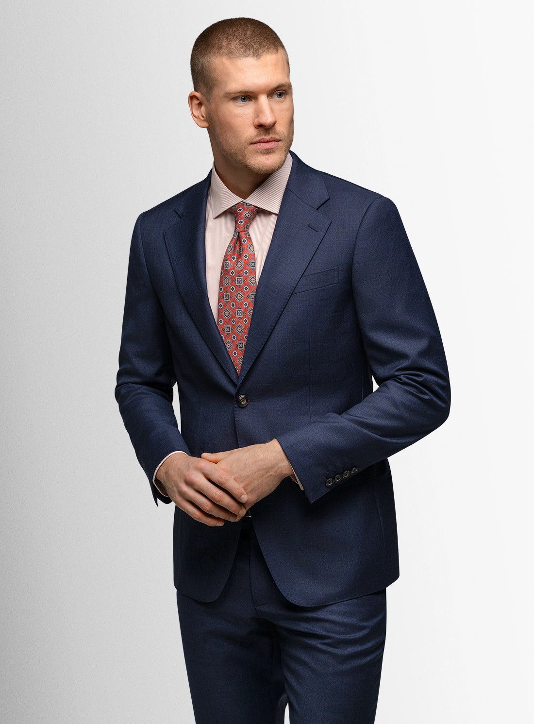 Man wearing a navy suit with a patterned tie on a light gray background