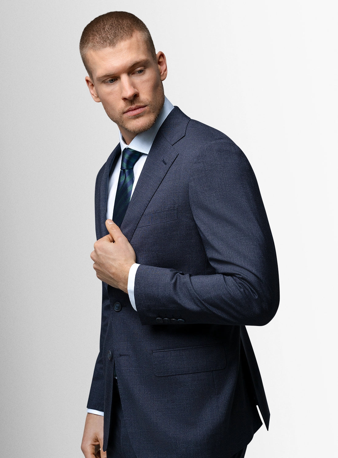 Man wearing a navy suit and tie against a light gray background
