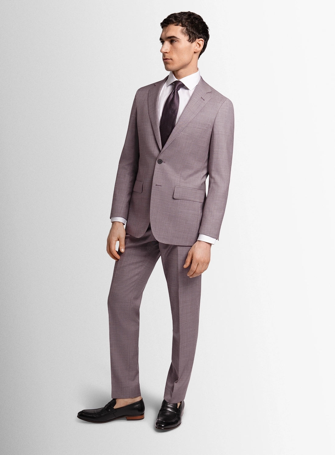 Man wearing a gray suit with a white shirt and black shoes on a light gray background