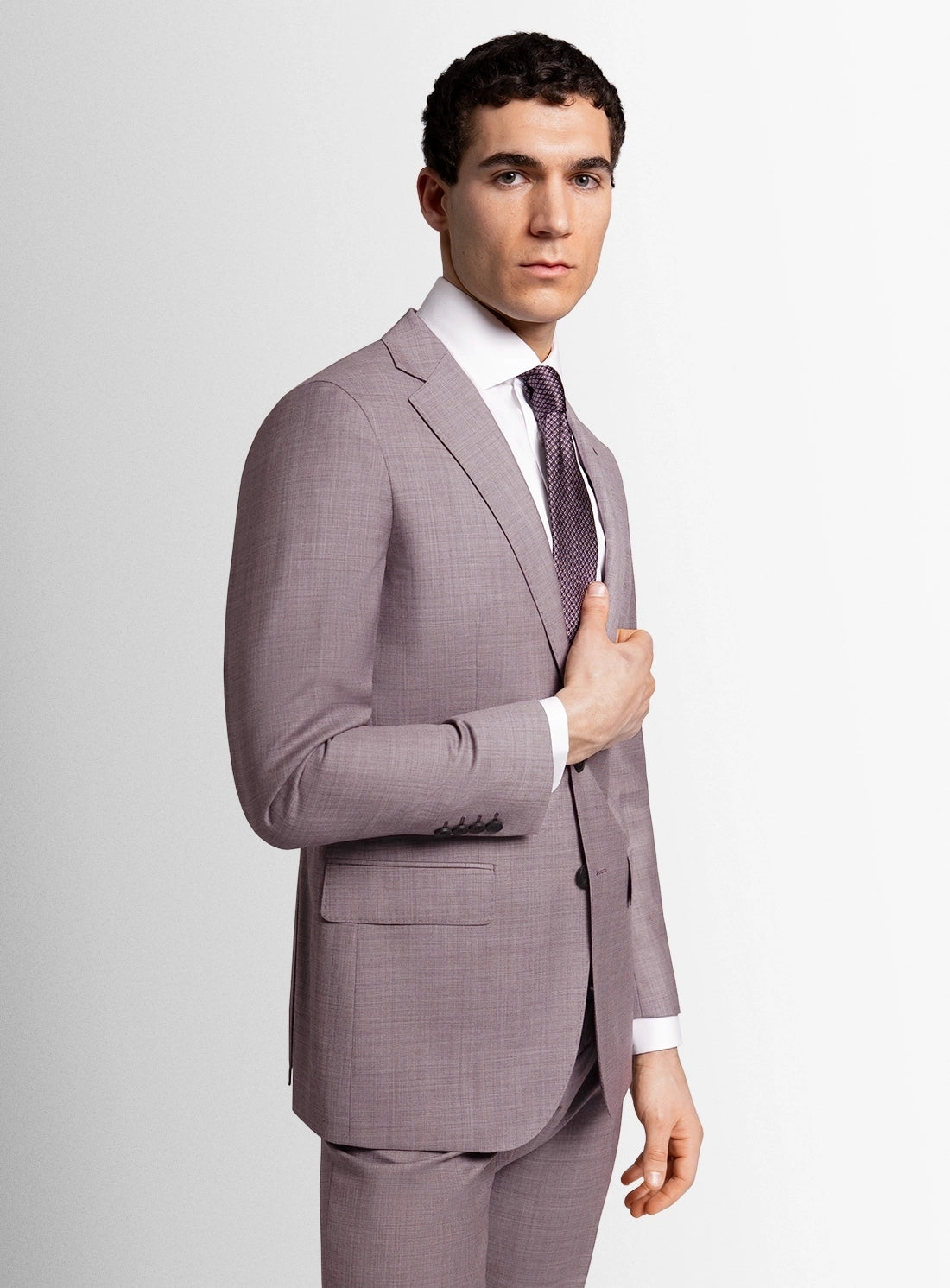 Man wearing a gray checkered suit with a white shirt and purple tie on a light gray background
