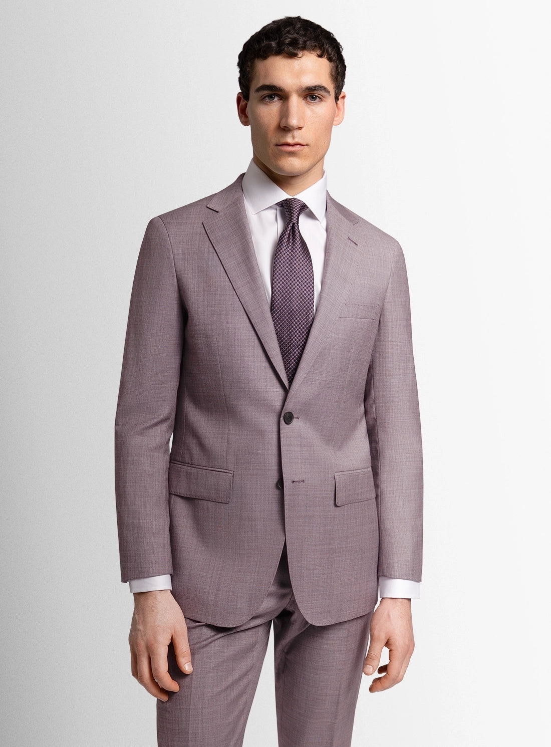 Man wearing a gray checkered suit with a white shirt and patterned tie on a light gray background