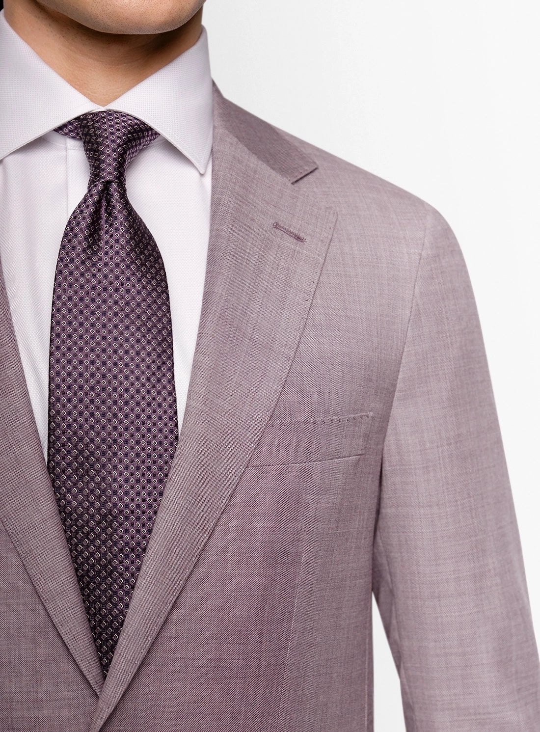 Gray suit jacket with a white shirt and purple patterned tie on a light gray background