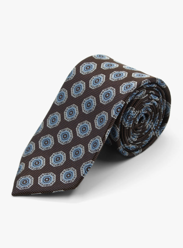 Rolled-up brown tie with blue geometric pattern on a white background