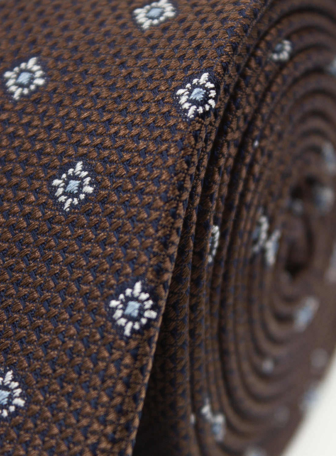 Close-up of a brown tie with white floral patterns