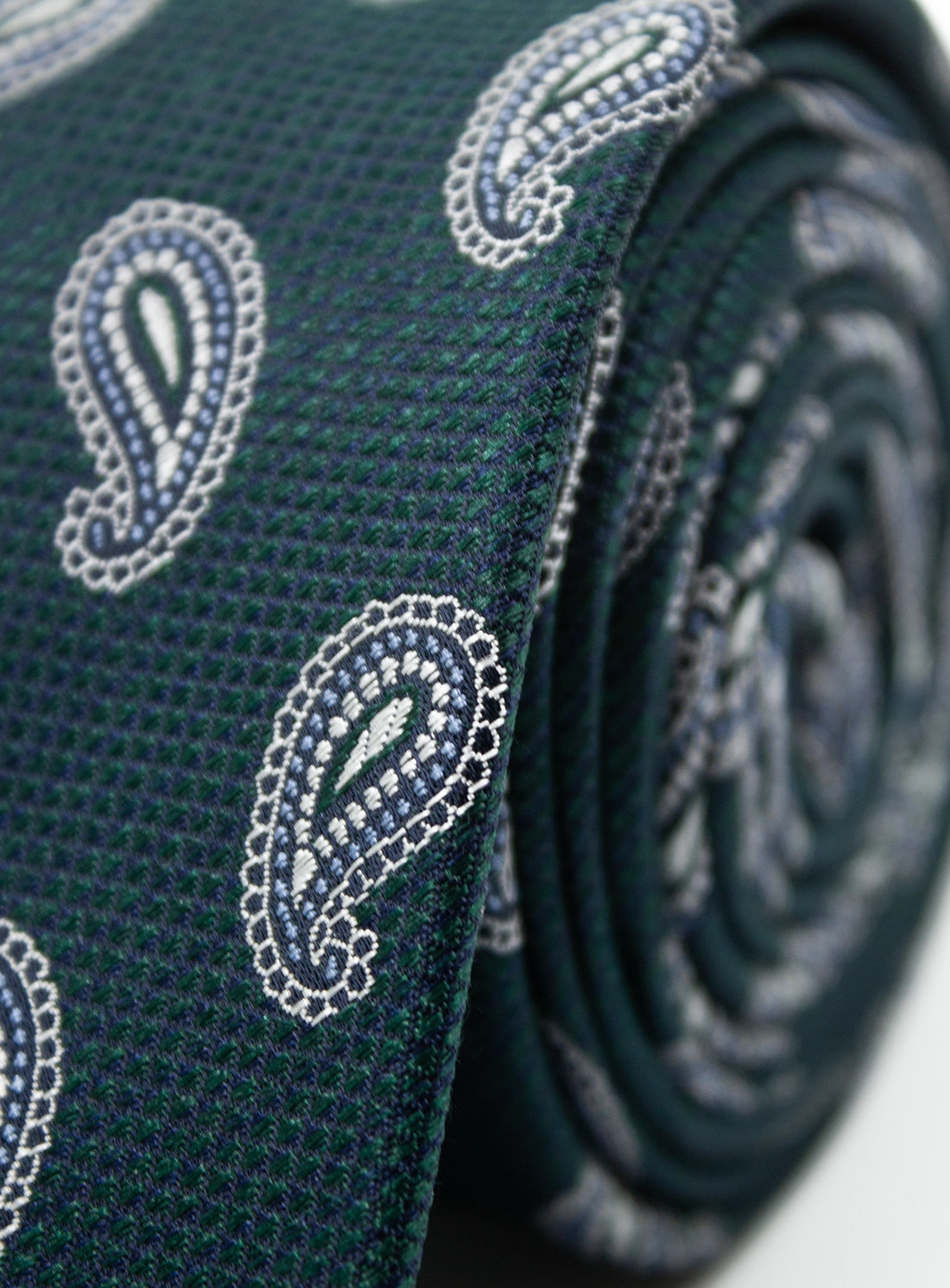 Close-up of a green tie with paisley patterns on a white background