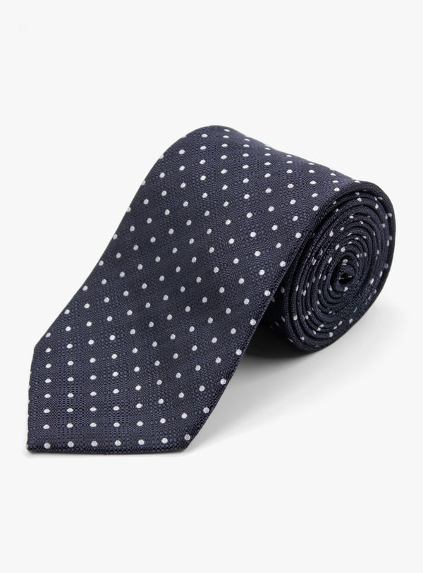 Navy blue tie with white polka dots on a light gray background