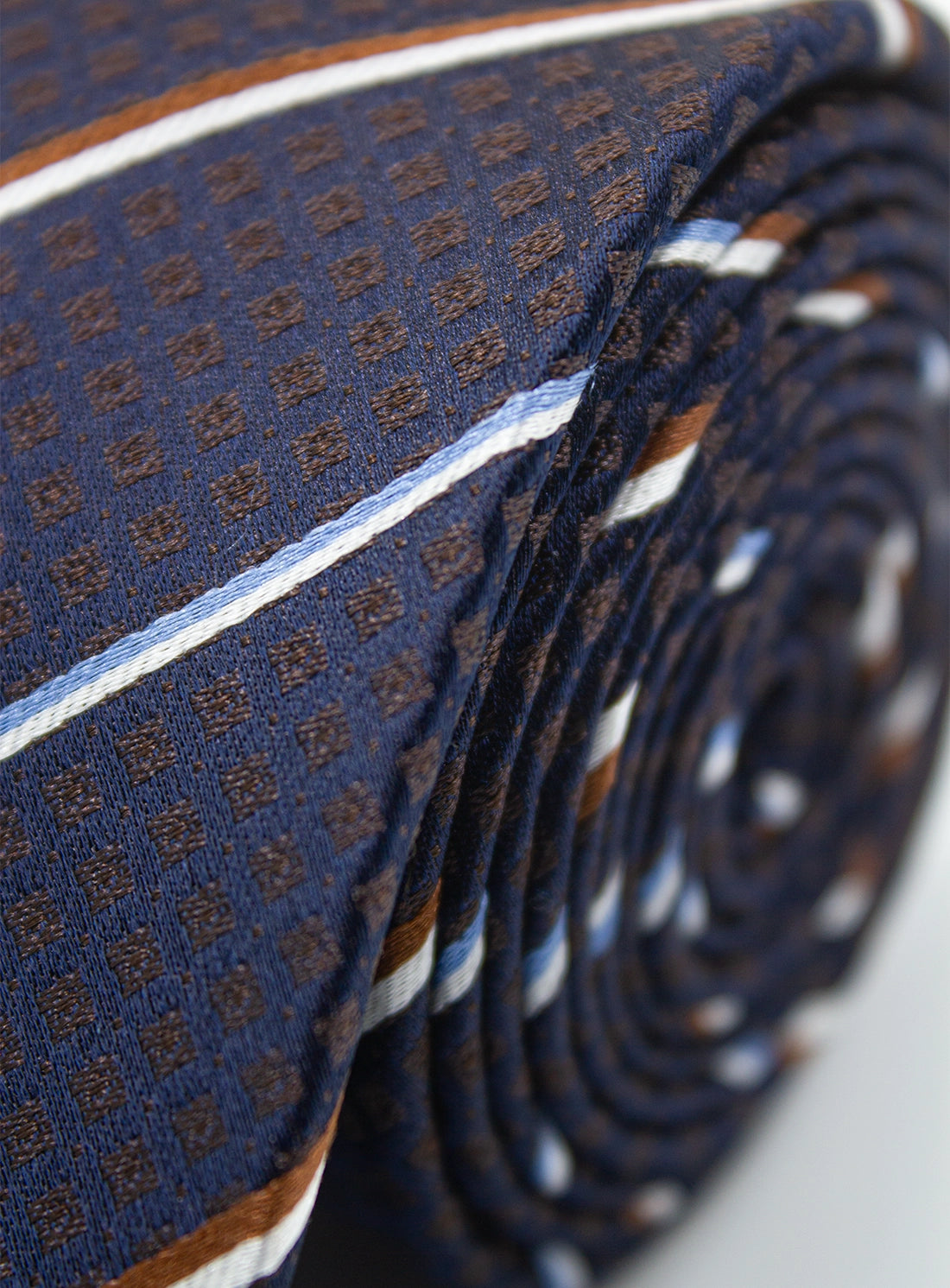 Close-up of a folded blue patterned tie on a light gray background