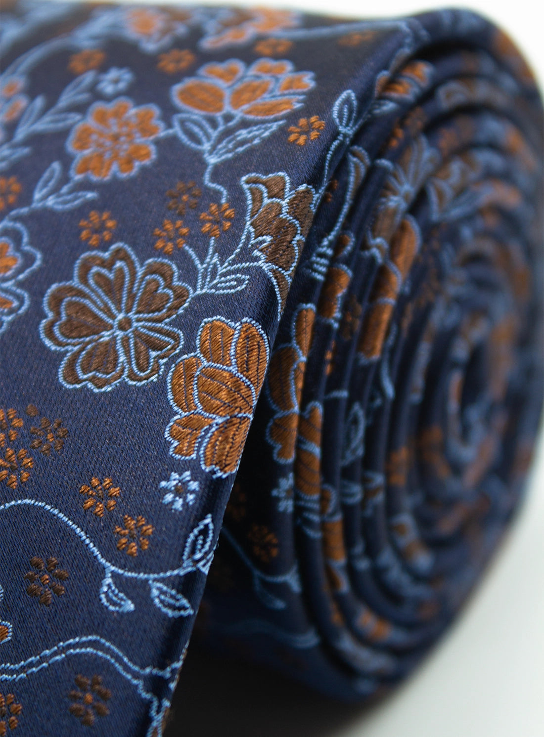 Folded blue tie with brown floral pattern on a white background
