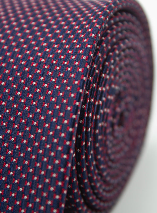 Close-up of a patterned tie with red and white details on a blue background