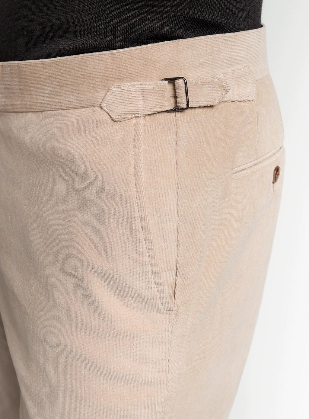 Close-up of beige pants with a belt and pocket detail on a white background