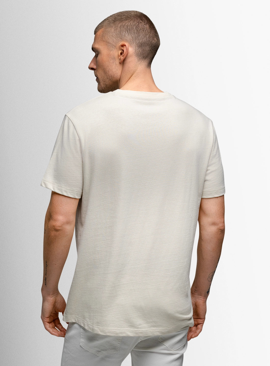 Man wearing a plain white t-shirt against a light gray background