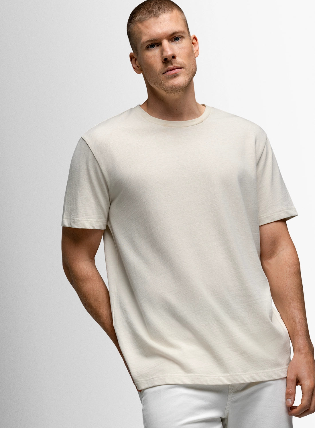 Man wearing a plain white t-shirt against a light gray background