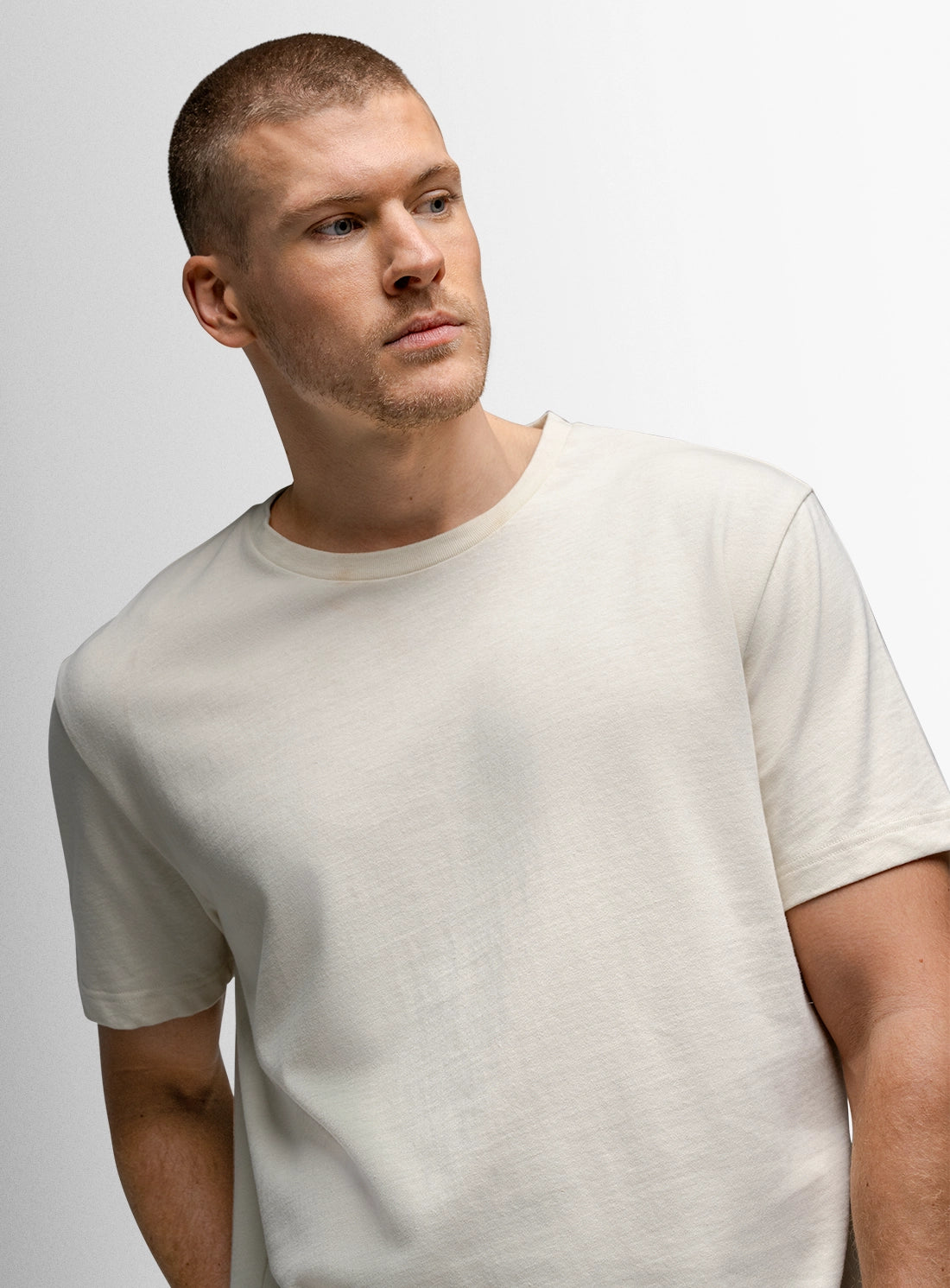Man wearing a plain white t-shirt against a light gray background