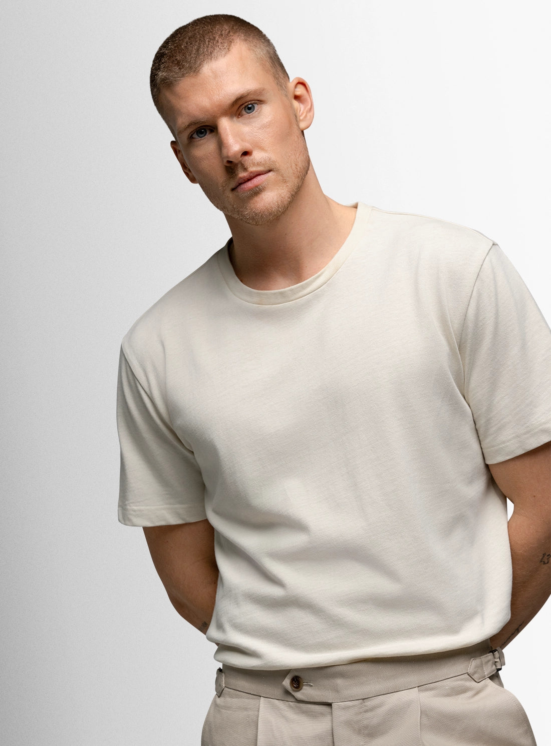 Man wearing a plain white t-shirt against a light gray background