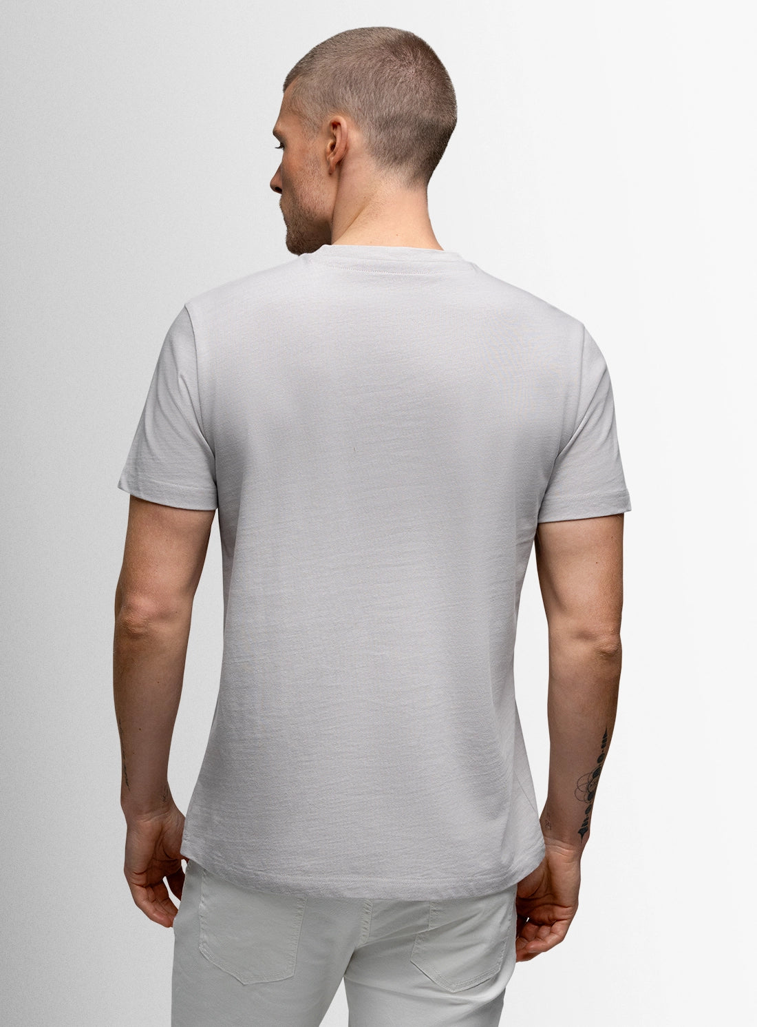 Man wearing a gray t-shirt and pants on a light gray background