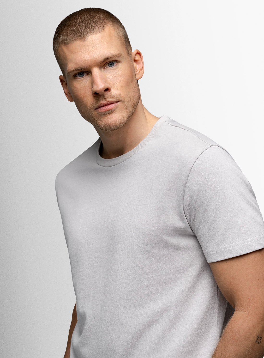 Man wearing a light gray t-shirt against a plain background