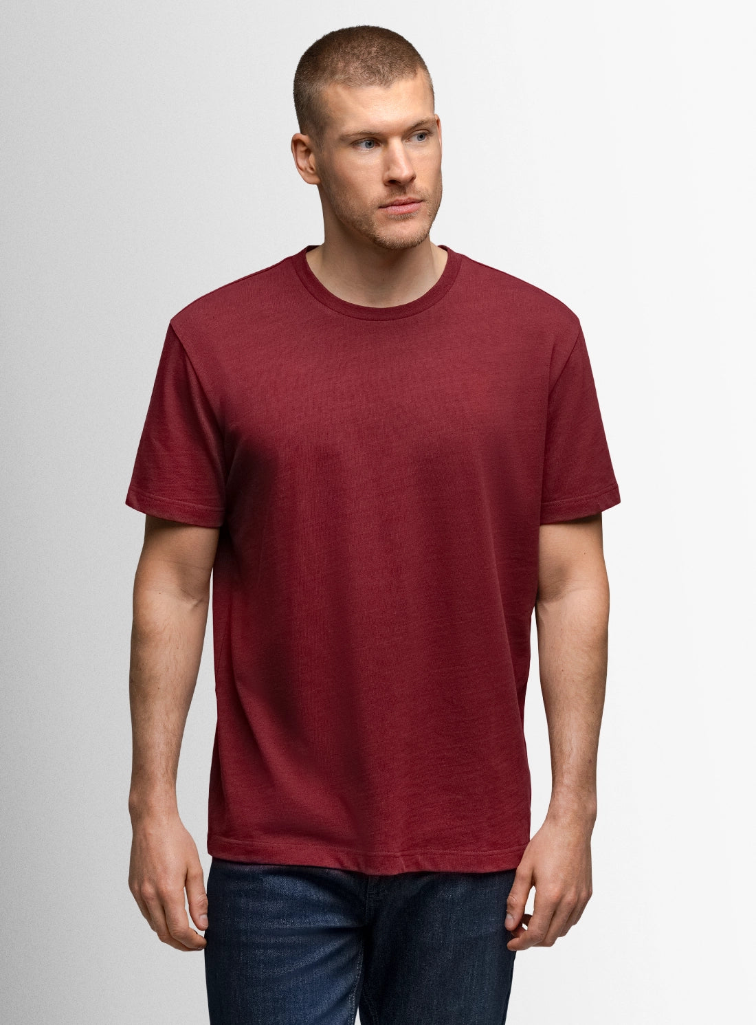 Man wearing a maroon t-shirt against a plain background