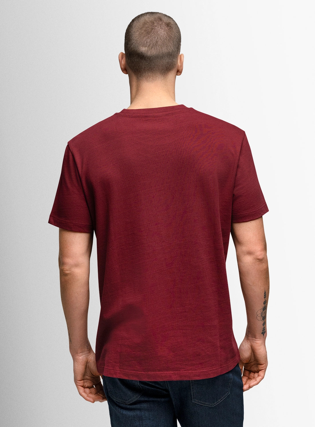 Man wearing a maroon t-shirt on a plain background