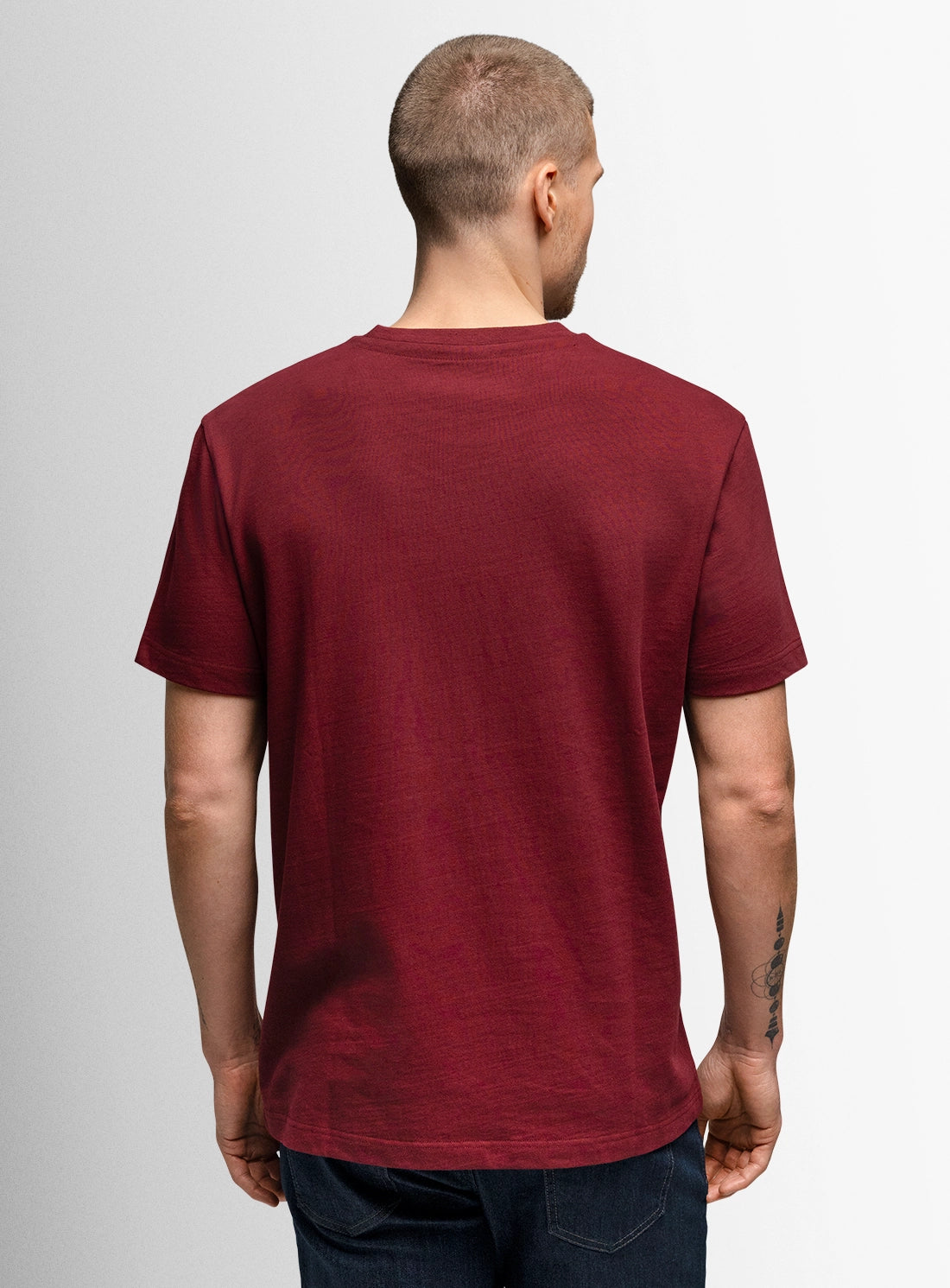 Man wearing a maroon t-shirt on a plain background