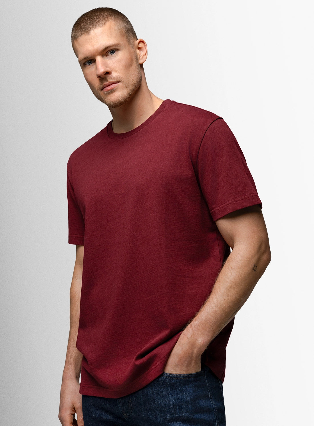 Man wearing a maroon t-shirt against a plain background