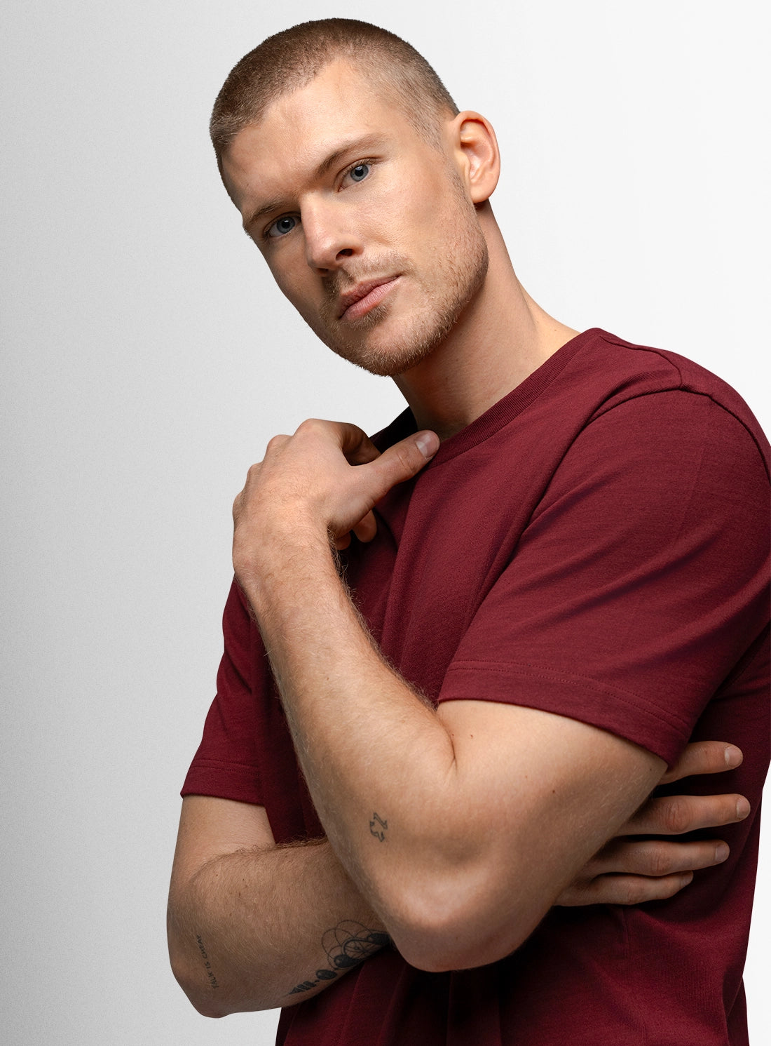 Man wearing a maroon t-shirt against a plain background