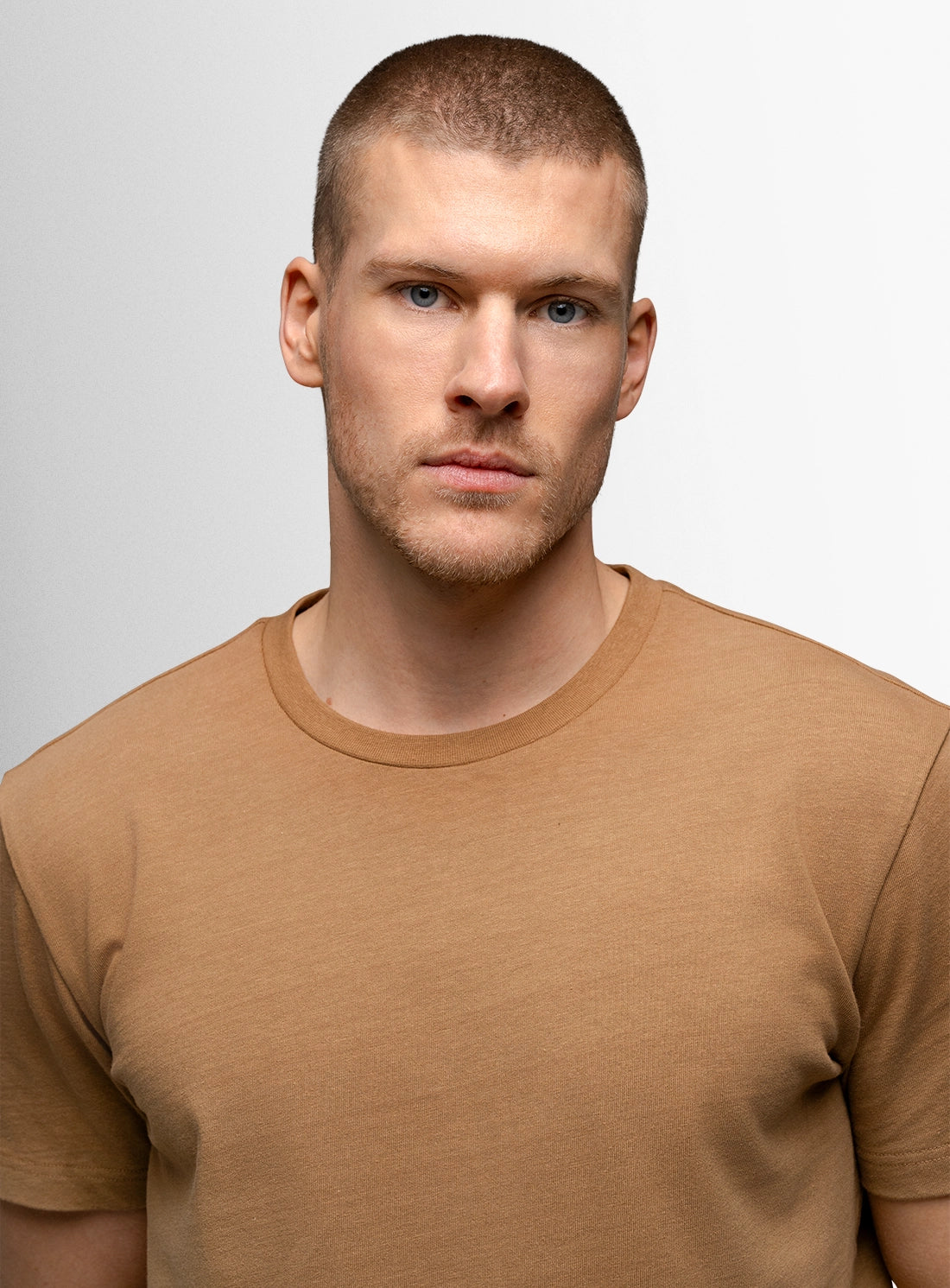 Man wearing a brown t-shirt against a plain background