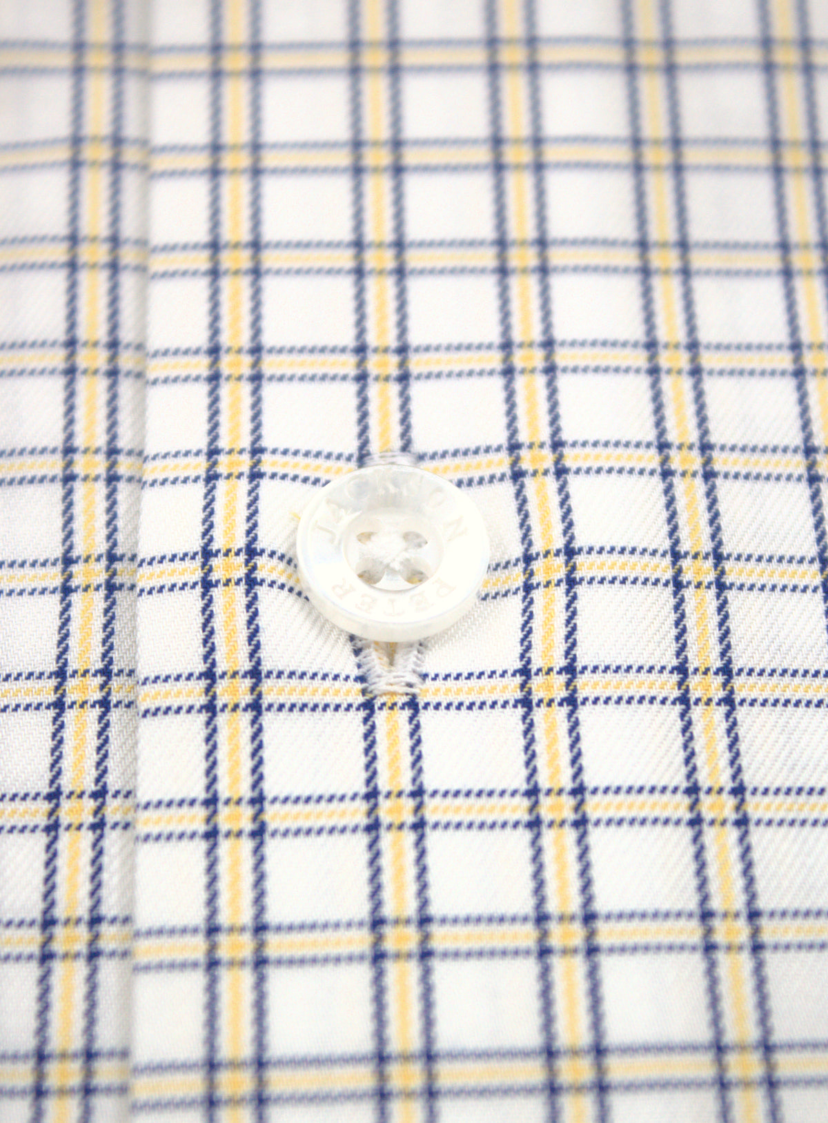 Close-up of transparent Peter Jackson button and yellow and navy mini plaid fabric