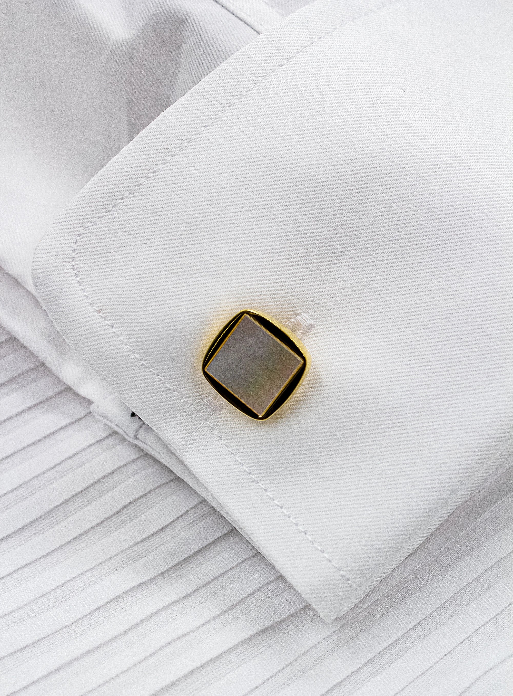 square gold with mother of pearl cufflinks in shirt close up